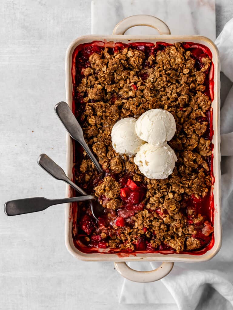 warm strawberry rhubarb crisp topped with cold ice cream 