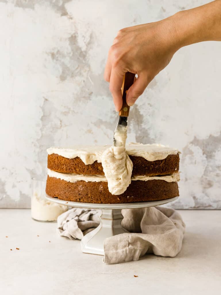 icing a cake with brown butter cream cheese buttercream