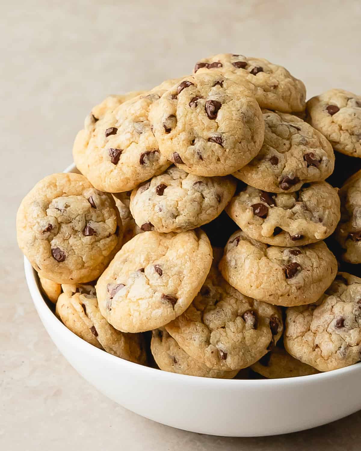These mini chocolate chip cookies are tiny,  bite sized cookies with lightly crisp, buttery edges with soft, chewy centers and tons of melty mini chocolate chips. This recipe for these mini cookies uses all the same ingredients of  classic chocolate chip cookies just baked into bite sized chocolate chip cookies.  Make these chocolate chip cookie bites in one bowl, with no chilling time needed. 
