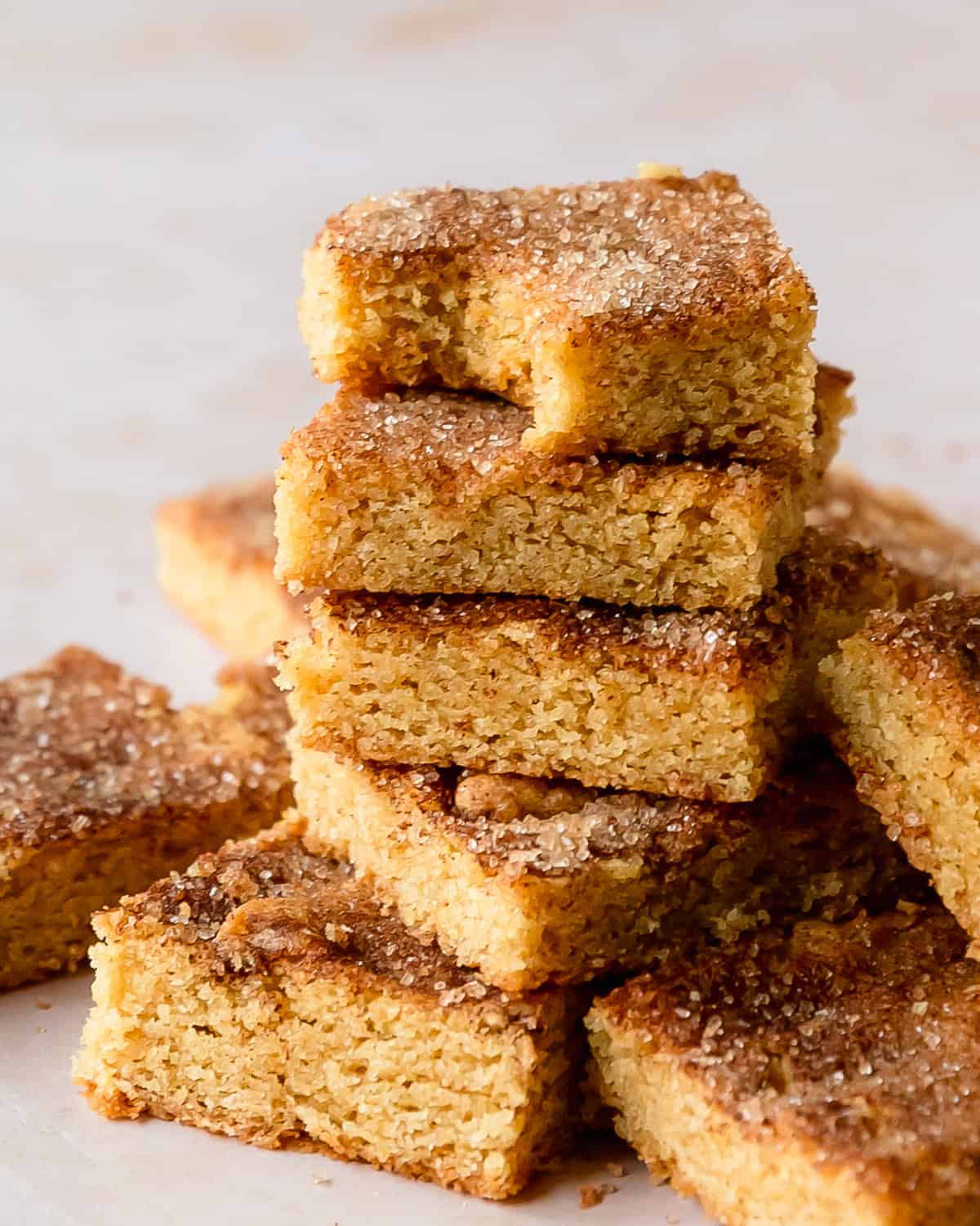 Snickerdoodle bars are soft and chewy, sweet and slightly tangy, cinnamon sugar coated snickerdoodle cookies made into wonderfully easy to make cookie bars. These snickerdoodle cookie bars are no chill, require no rolling and are the perfect dessert to feed a crowd. Make these cinnamon sugar bar cookies the next time you want a pan full of cozy and flavorful cookies.