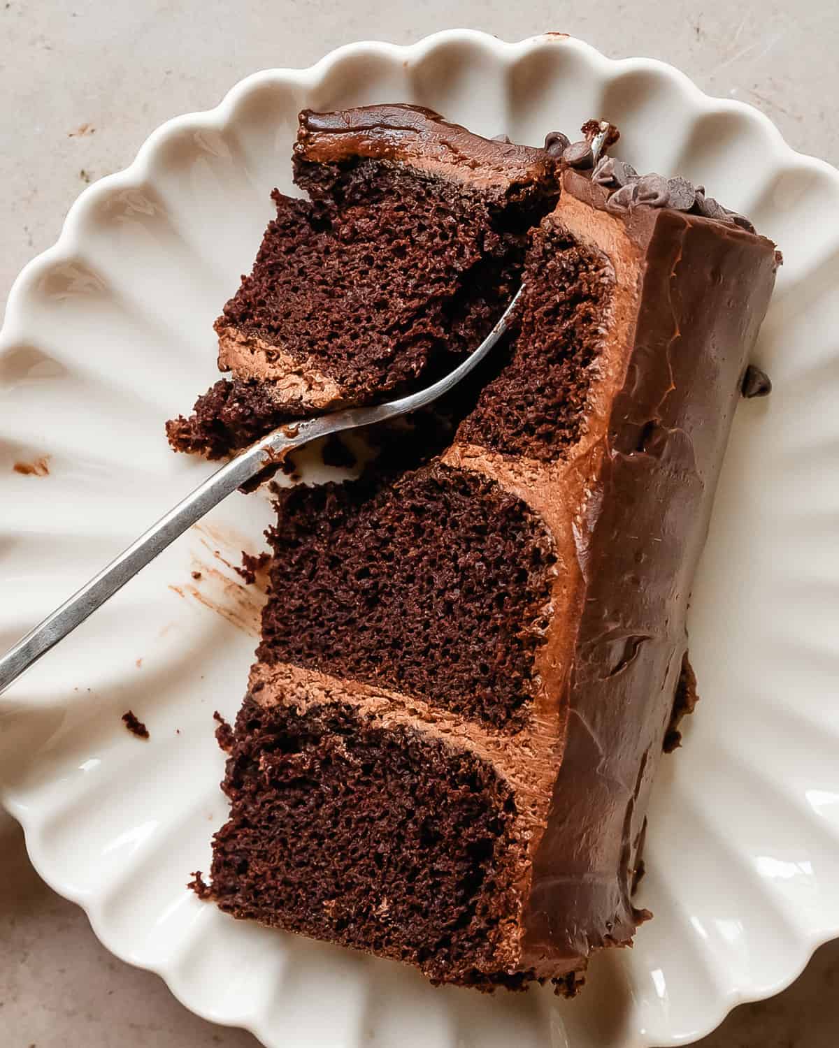 Triple Chocolate Cake is moist and fudgy three chocolate cake, layered with a rich and creamy chocolate buttercream frosting. This decadent chocolate layer cake is topped with a glossy chocolate ganache and chocolate chips. What makes this the best chocolate cake is how easily all the layers come together to make a truly remarkable triple chocolate fudge cake.