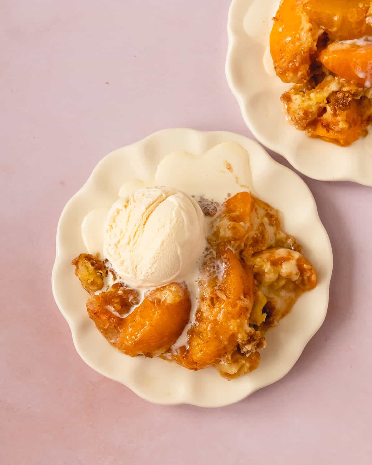 Peach Cobbler with Cake Mix on a plate with melting ice cream.