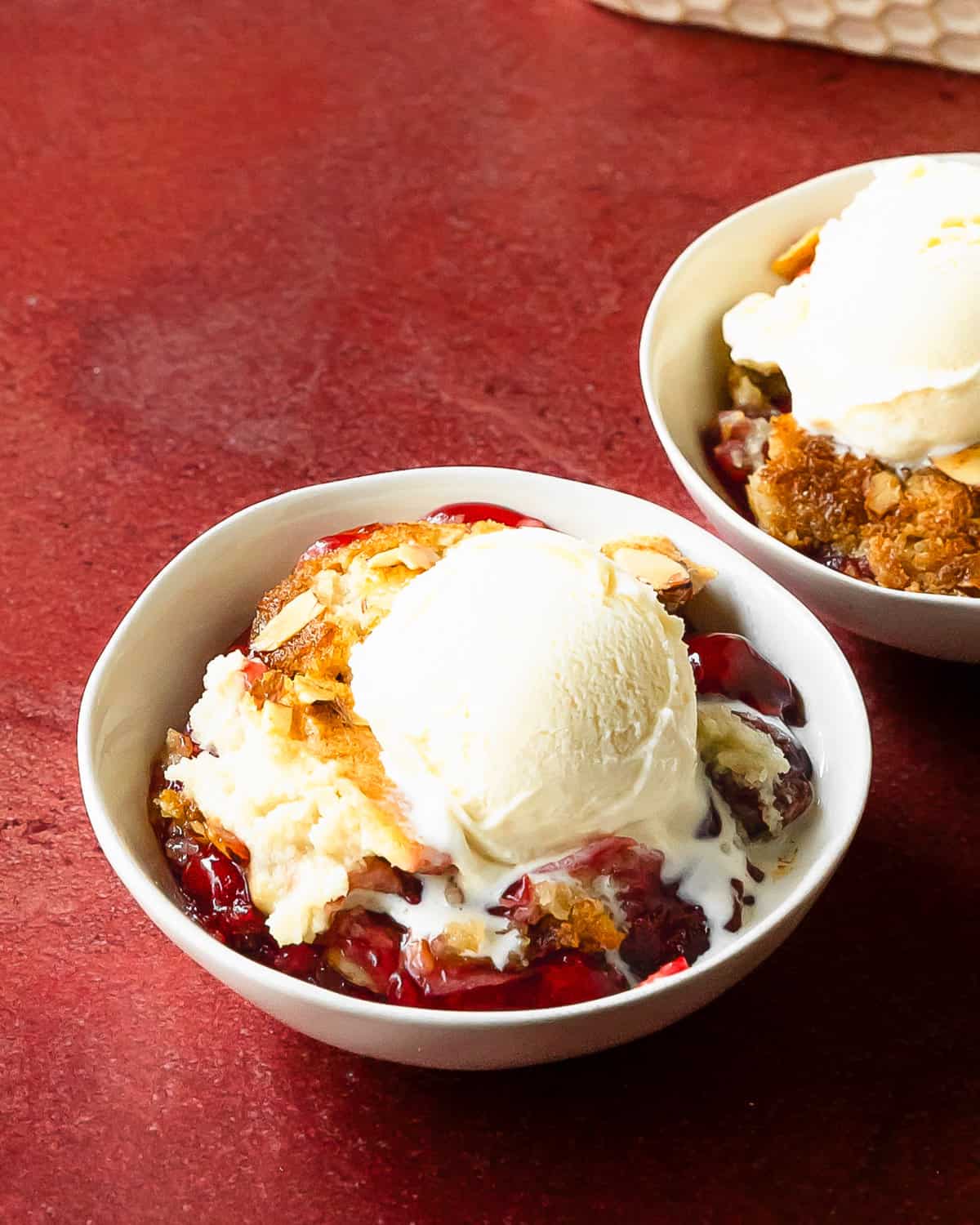 Cherry dump cake is an easy to make cherry cobbler with cake mix dessert. This recipe for cherry dump cake comes together quickly with pantry basics such as cake mix, cherry pie filling, canned or fresh cherries and butter. Top this cherry cobbler dump cake with vanilla ice cream for the perfect easy baked dessert. 