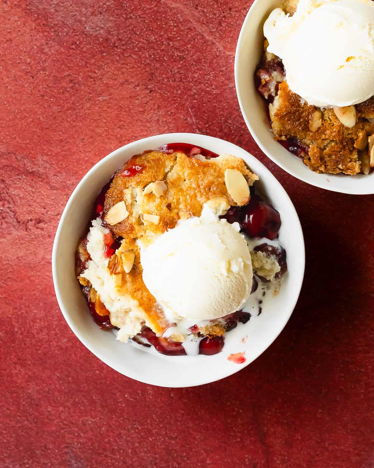 Cherry dump cake is an easy to make cherry cobbler with cake mix dessert. This recipe for cherry dump cake comes together quickly with pantry basics such as cake mix, cherry pie filling, canned or fresh cherries and butter. Top this cherry cobbler dump cake with vanilla ice cream for the perfect easy baked dessert.