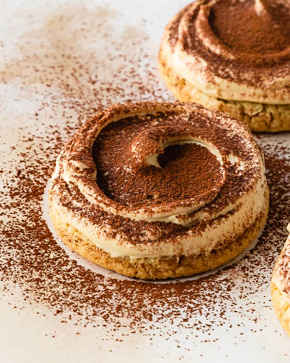 Tiramisu cookies are soft and chewy coffee sugar cookies topped with a rich a creamy espresso mascarpone frosting and a light dusting of cocoa powder. If tiramisu was a cookie, it would be these mascarpone cookies. What I love most about these tiramisu sugar cookies are that they require no chilling time, are super easy to make and taste just like the classic tiramisu dessert. 