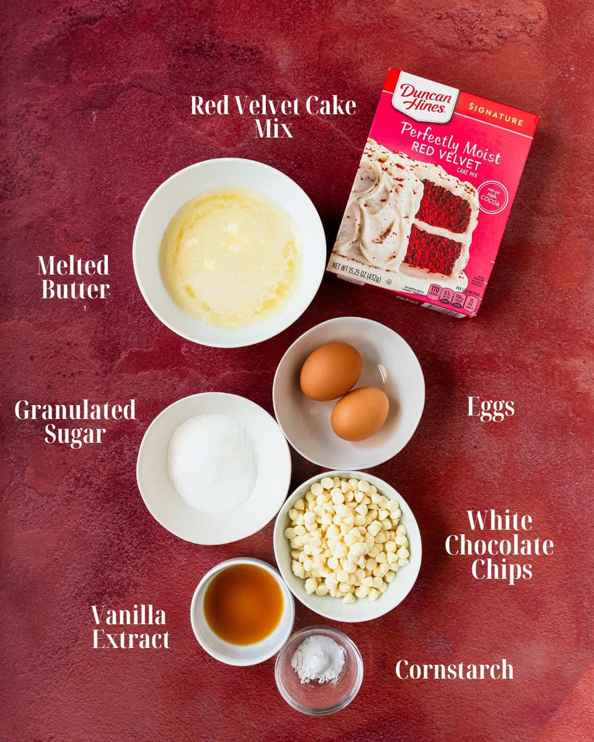 Gather your preferred red velvet cake mix, cornstarch, melted butter, eggs, granulated sugar, vanilla extract and white chocolate chips. 