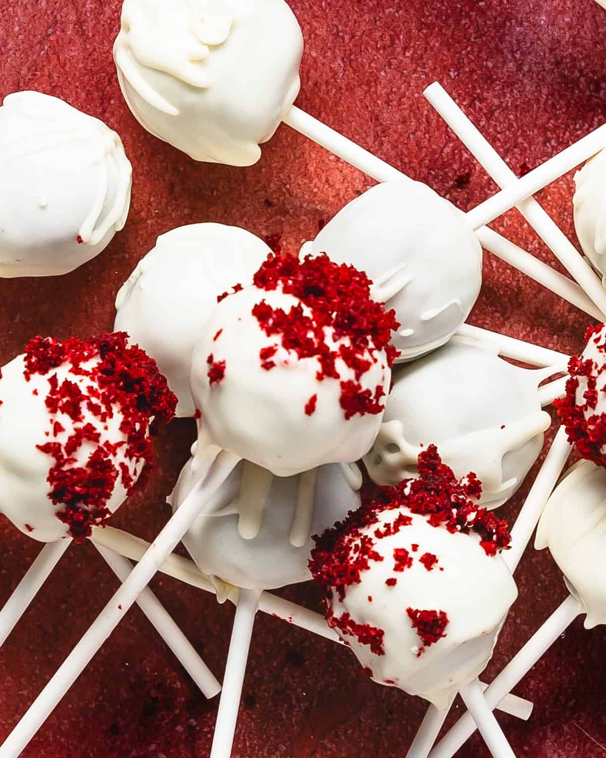 Red velvet cake pops are decadent and delicious red velvet cake balls made from red velvet cake and cream cheese frosting covered in white chocolate. These red velvet truffles are super simple to make using box cake mix, store bought frosting and white chocolate candy melts.