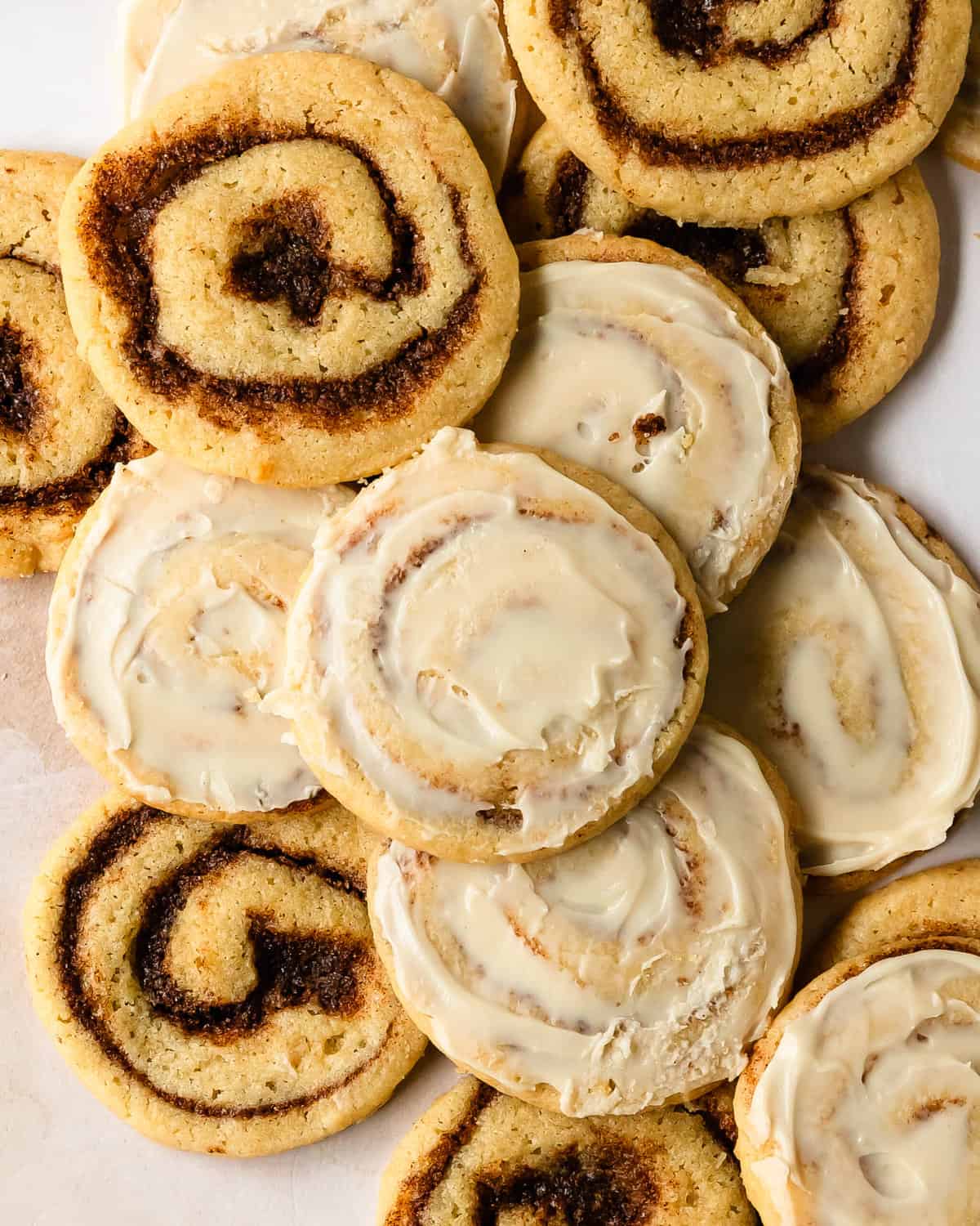 Cinnamon roll cookies are are a fun slice and bake cookie inspired by decadent cinnamon rolls. They’re soft and buttery sugar cookies swirled with a classic cinnamon roll filling. Top these soft cinnamon cookies with an easy and irresistible cream cheese icing to make these the best frosted cinnamon roll cookies everyone will love.