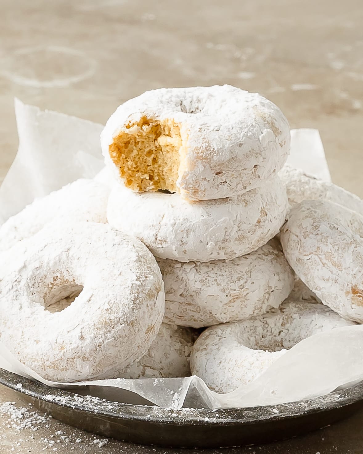 Powdered sugar donuts are soft, moist and fluffy, lightly spiced baked donuts coated in powdered sugar. These cake-style powdered donuts are quick and easy to make using two bowls, a whisk and a donut pan. If you can make muffins, you can make these cozy powder sugar donuts.