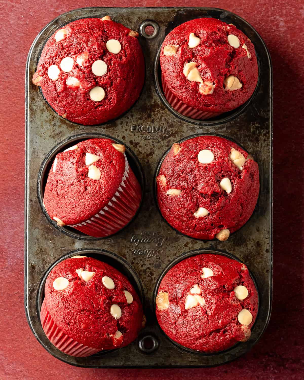 Red velvet muffins are soft, moist and fluffy bakery style muffins that taste and look just like a classic red velvet cake. White chocolate chips are studded throughout these vibrant velvet muffins for the perfect color and flavor contrast. These red velvet white chocolate muffins are the perfect quick and easy to make breakfast for any occasion.  