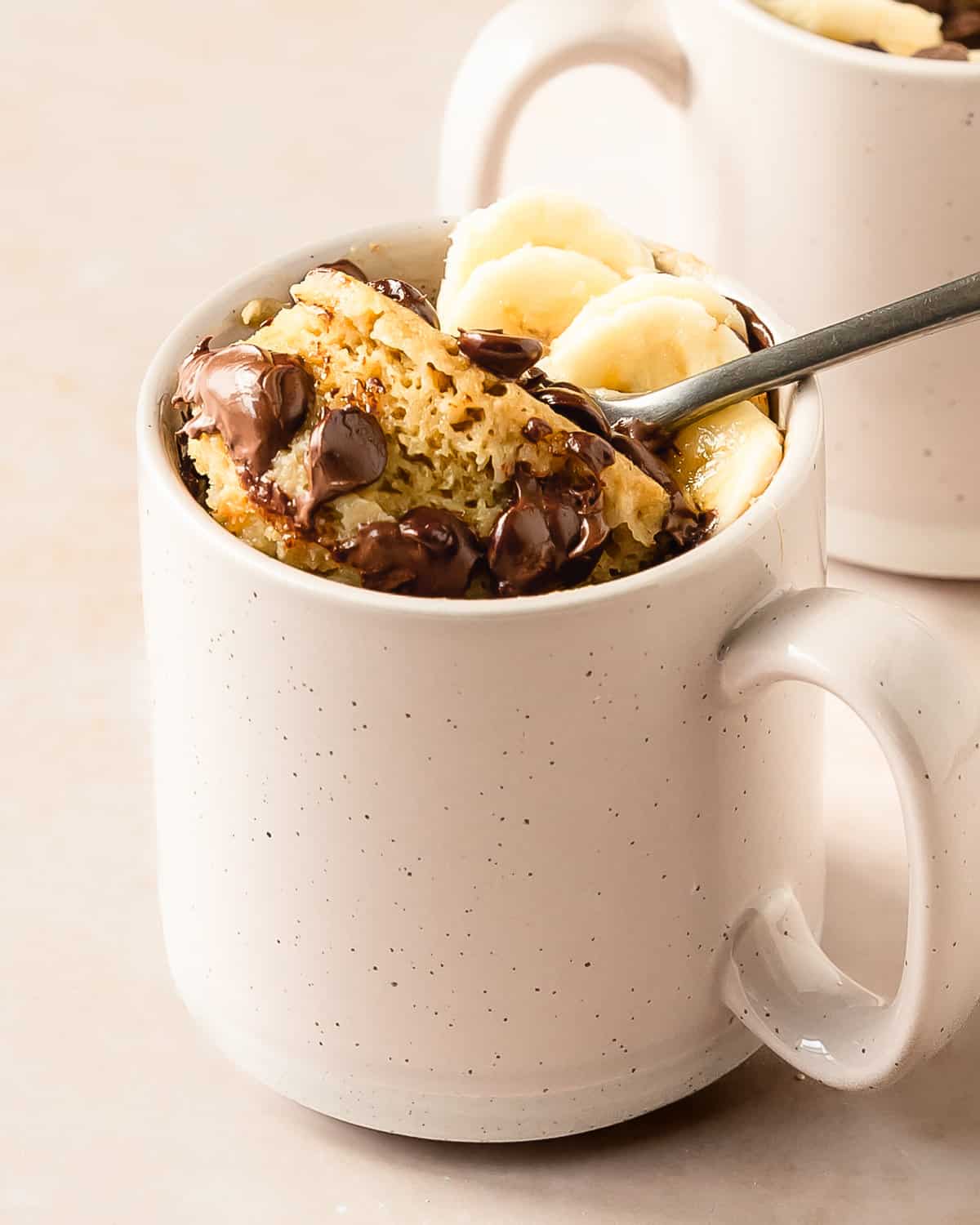 Banana mug cake is a moist, fluffy and super easy mug cake recipe that takes under 5 minutes to make. This banana cake in a mug is especially delicious when topped with lots of melty chocolate chips. Make this cozy banana bread in a mug cake for the perfect single serve breakfast, snack or dessert. 