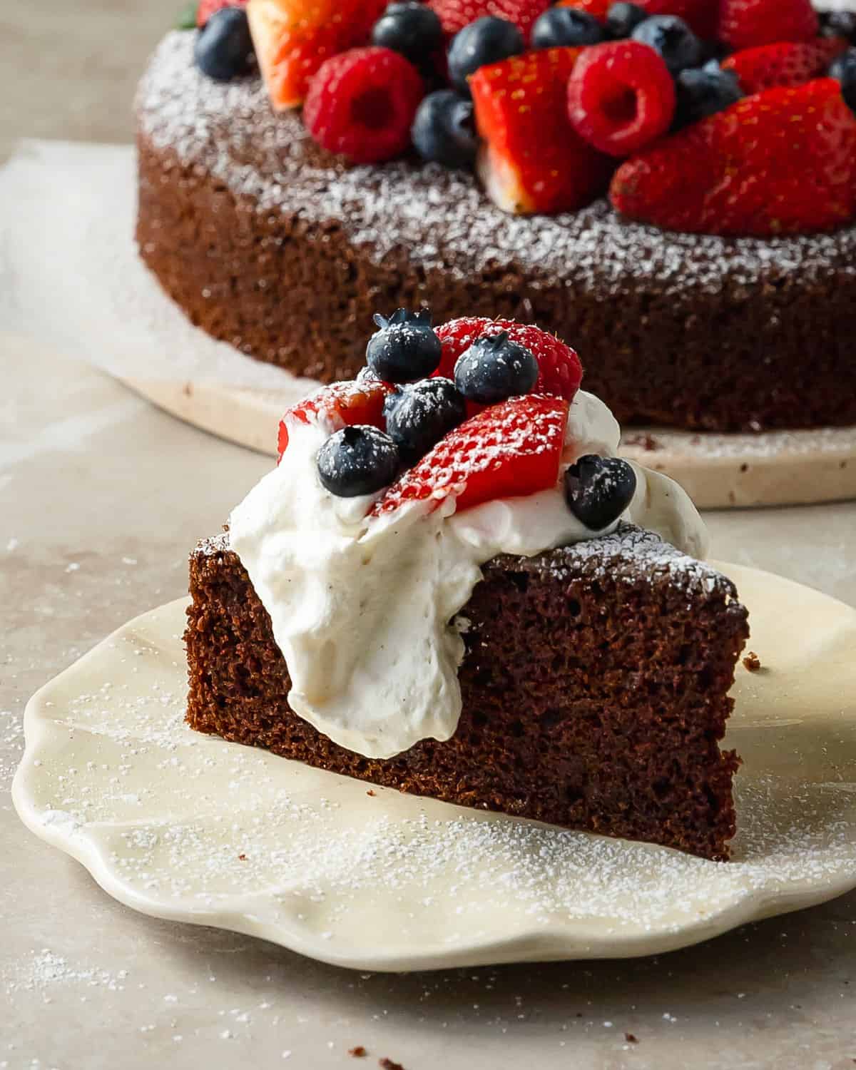 Chocolate olive oil cake is a deeply moist and tender chocolate cake made with rich and earthy olive oil. Top this simple olive oil chocolate cake with berries and fresh whipped cream for the perfect easy to make dessert. 