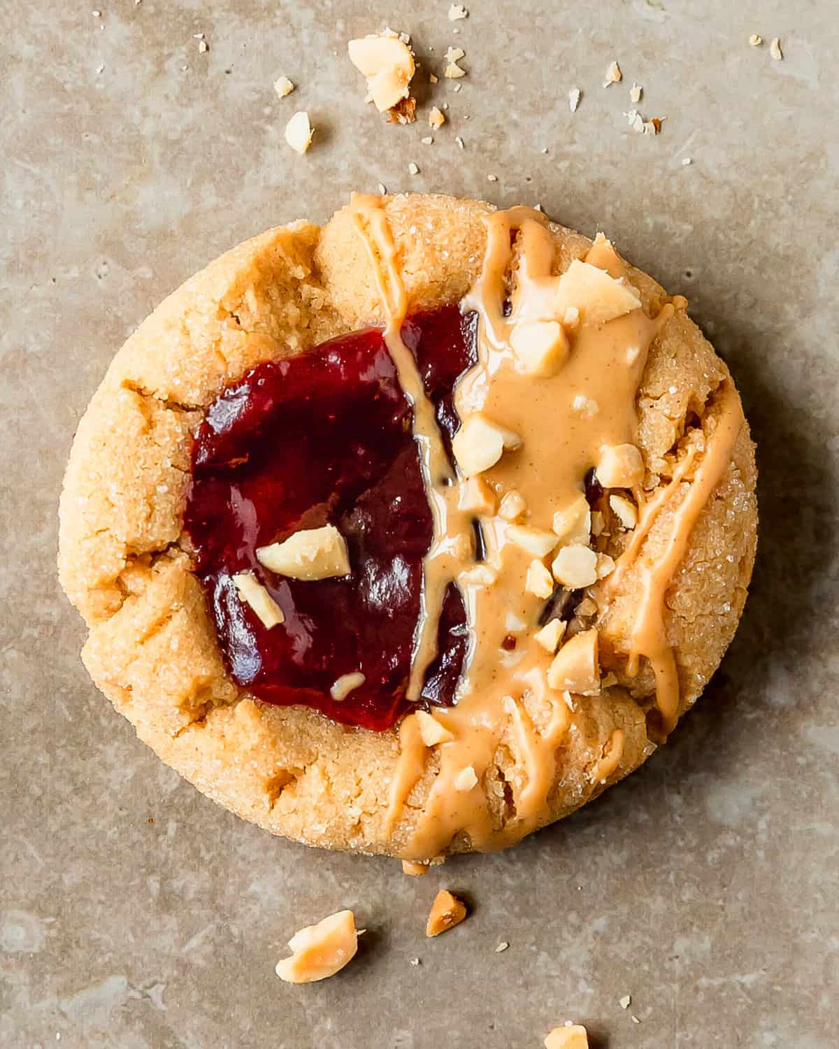 Peanut butter and jelly cookies are soft and chewy peanut butter cookies, rolled in a crunchy sugar coating, with a strawberry jam filled center. Top these easy to make peanut butter jelly cookies with a dollop of more jelly, a drizzle of PB and chopped peanuts after baking. These pb and j cookies are just like the classic sandwich in cookie form.