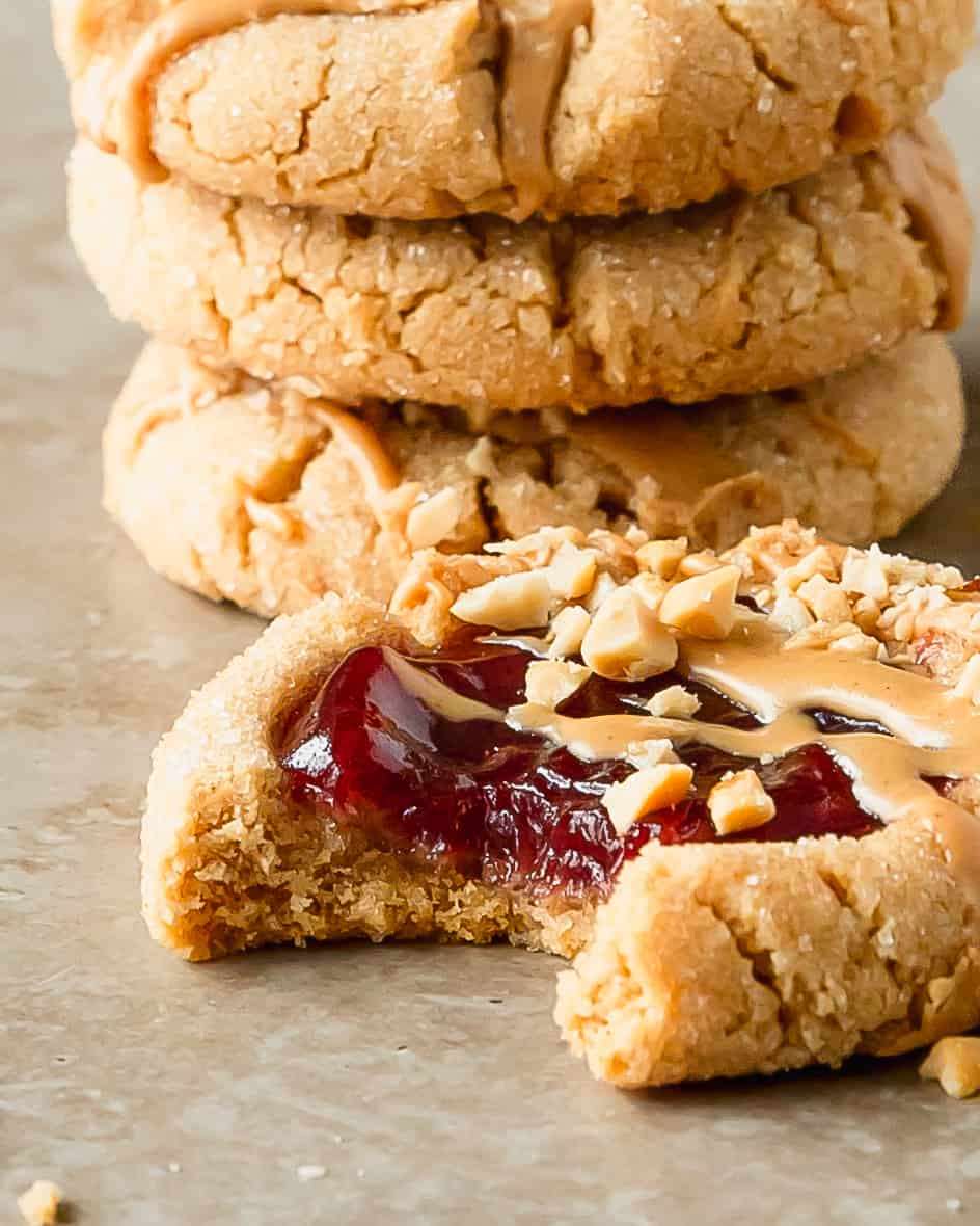 Peanut butter and jelly cookies are soft and chewy peanut butter cookies, rolled in a crunchy sugar coating, with a strawberry jam filled center. Top these easy to make peanut butter jelly cookies with a dollop of more jelly, a drizzle of PB and chopped peanuts after baking. These pb and j cookies are just like the classic sandwich in cookie form. 