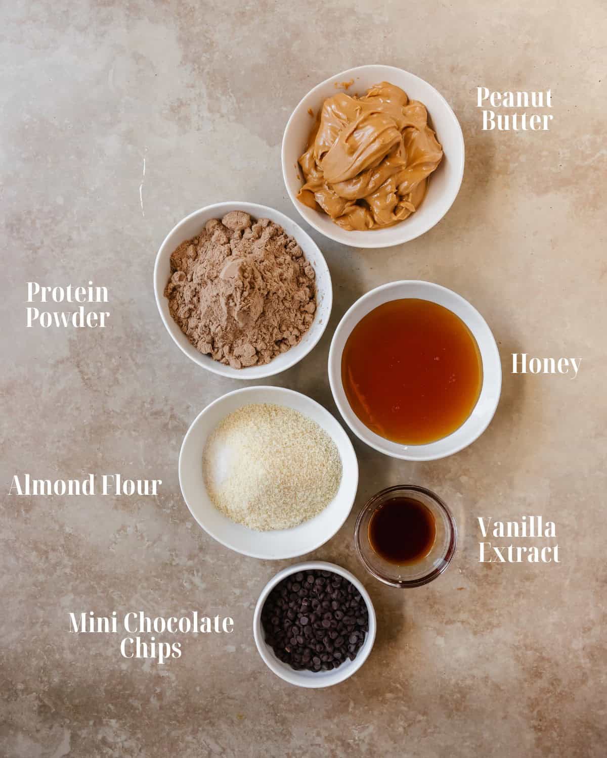 Gather peanut butter, protein powder, honey or maple syrup, almond flour, vanilla extract, salt and chocolate chips.