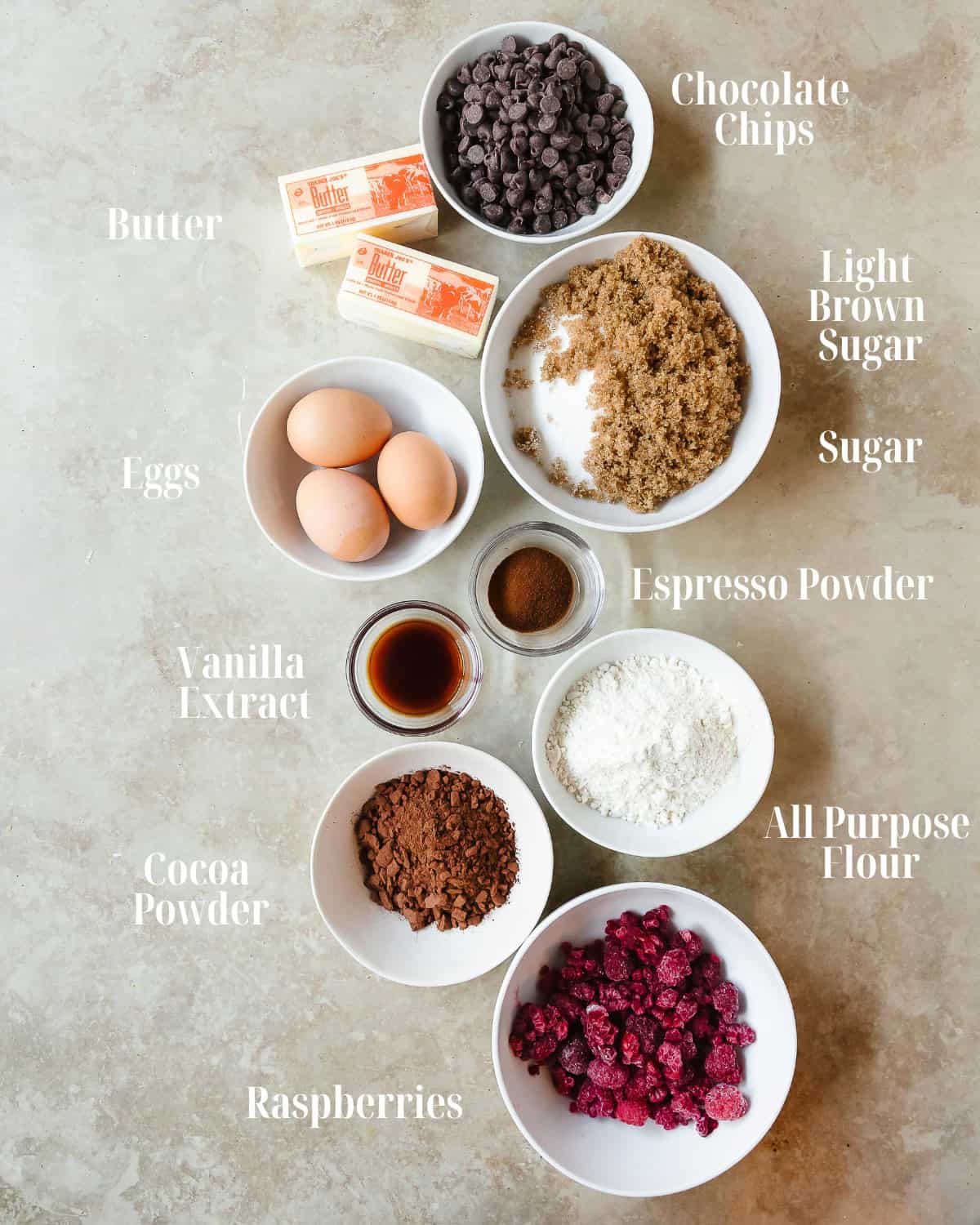 Gather butter, chocolate chips, espresso powder, eggs, sugar, light brown sugar, vanilla extract, salt, cocoa powder, flour and raspberries.