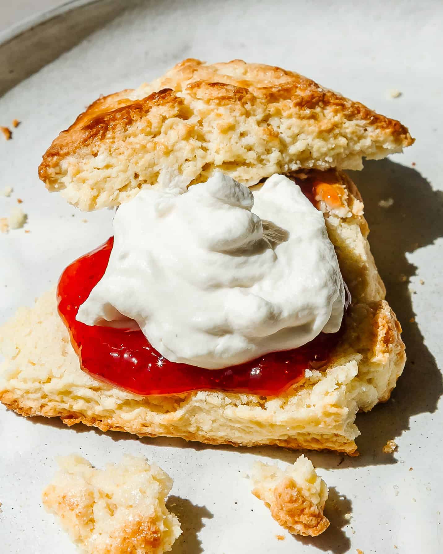 Flaky homemade buttermilk scones with cream and jam.
