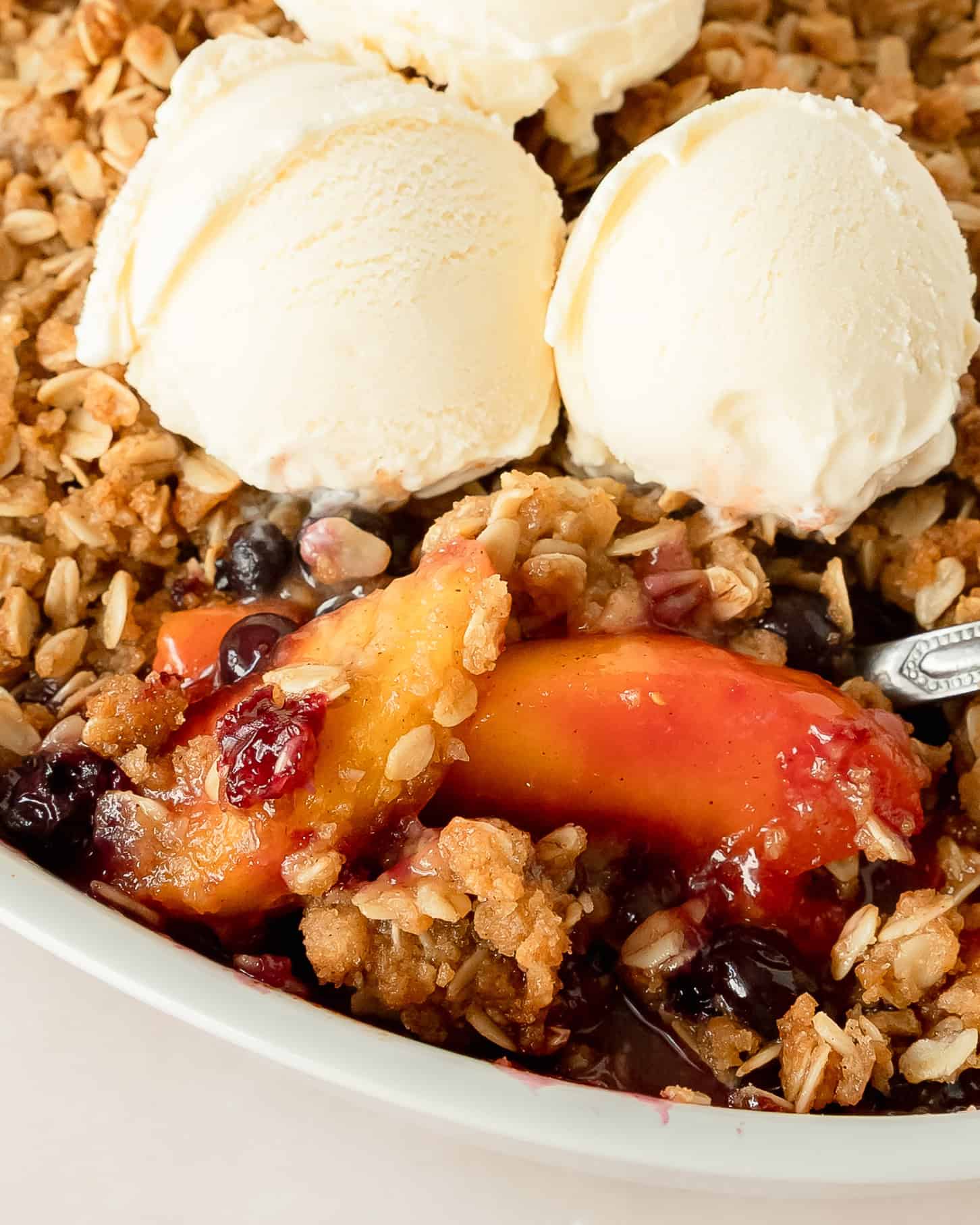 Peach blueberry crisp with buttery oat topping and baked fruit filling.