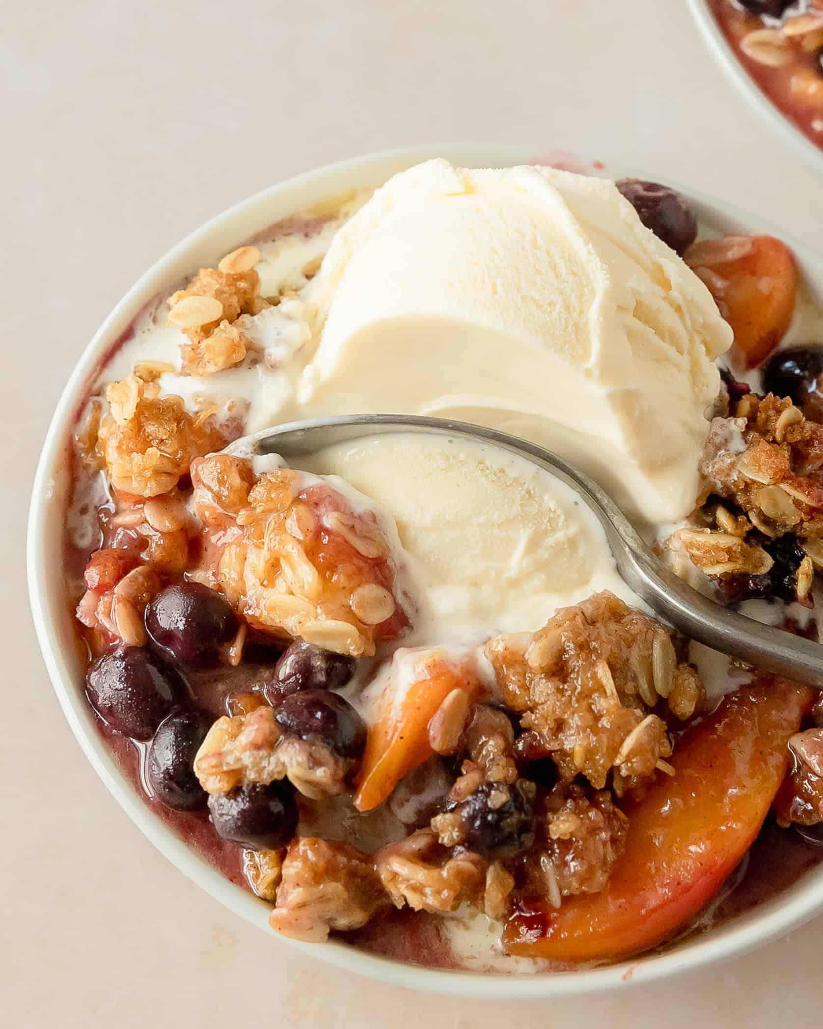 Peach blueberry crisp with a golden oat topping served warm in a baking dish.
