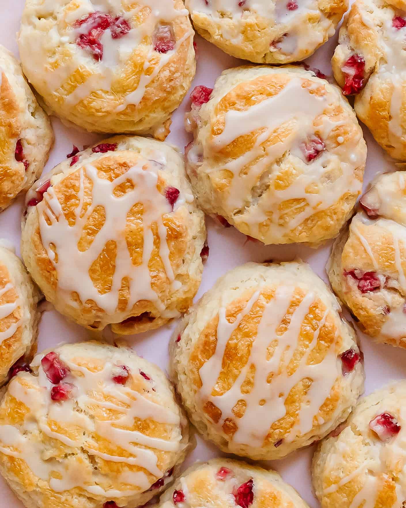 Close-up of flaky strawberry biscuits with a sweet glaze dripping down the sides.