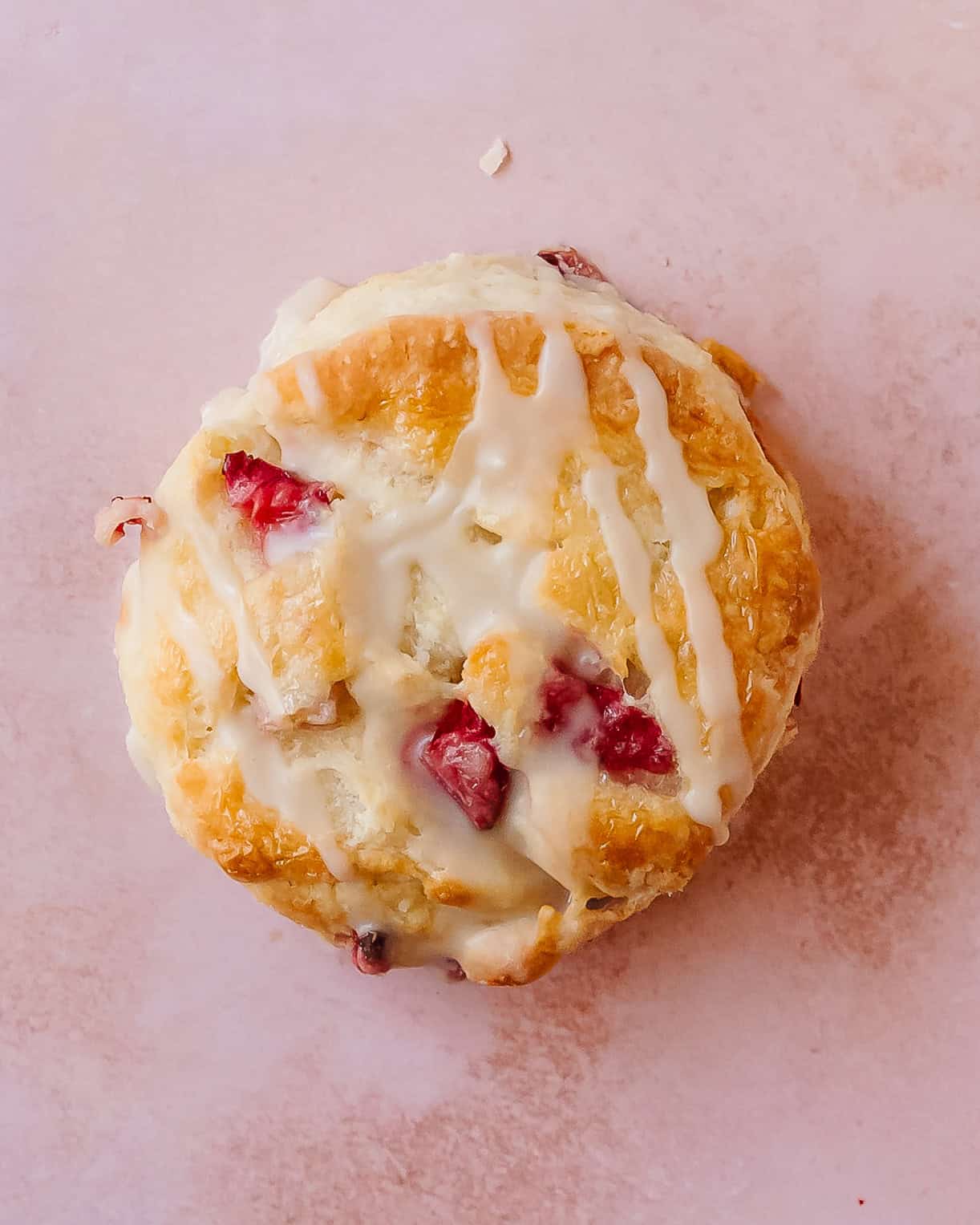 Close-up of flaky strawberry biscuits with a sweet glaze dripping down the sides.