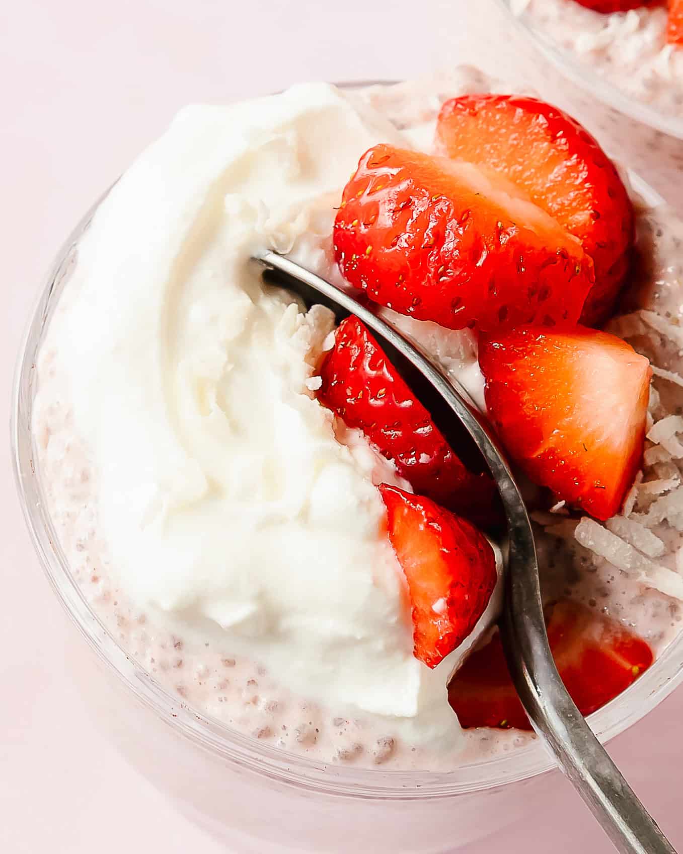 Close-up of strawberry chia seed pudding with fresh strawberries and a spoon.