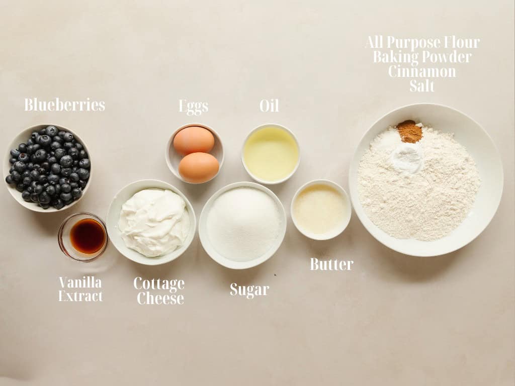 Ingredients for blueberry cottage cheese muffins laid out in white bowls.