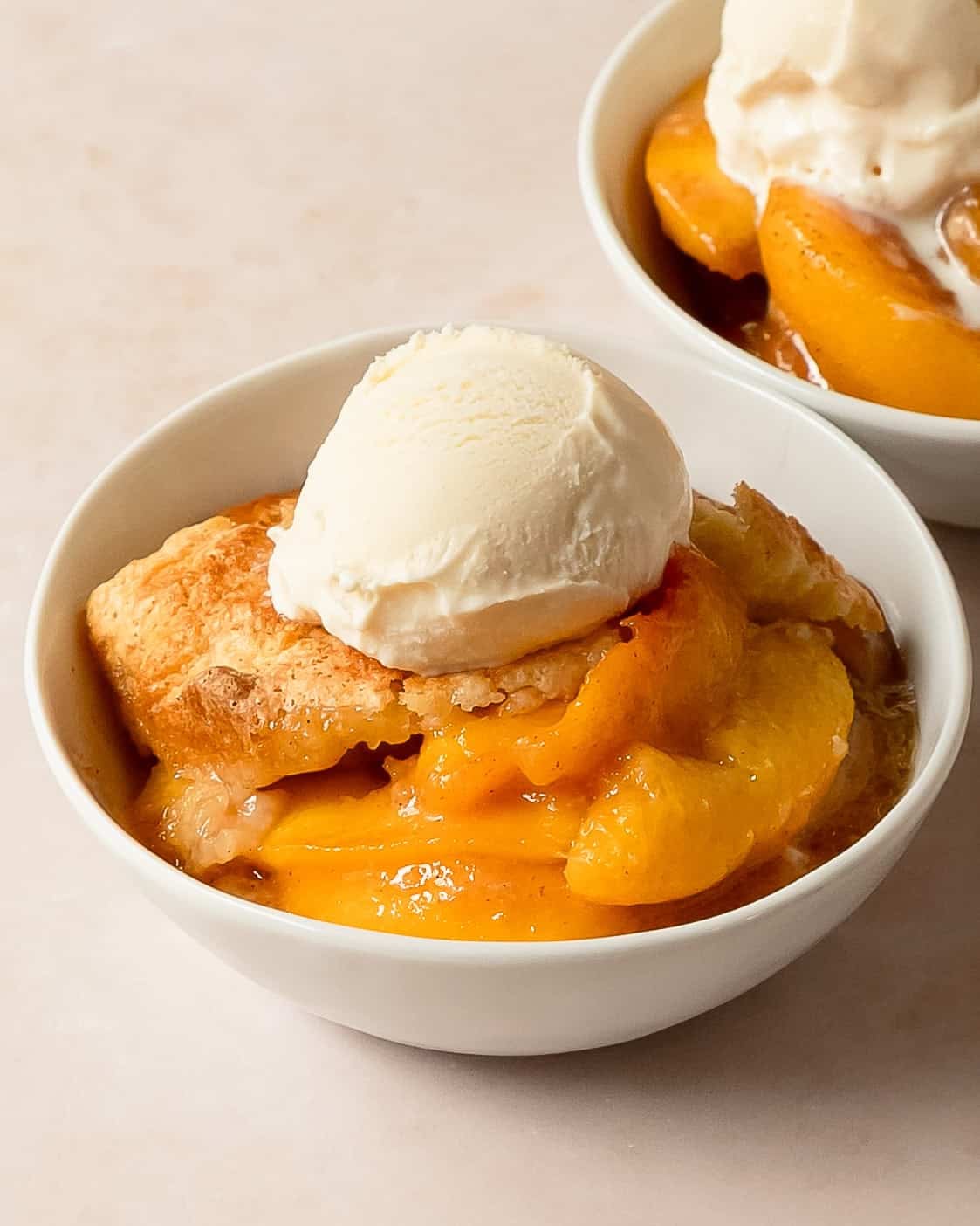 Frozen peach cobbler served with vanilla ice cream.