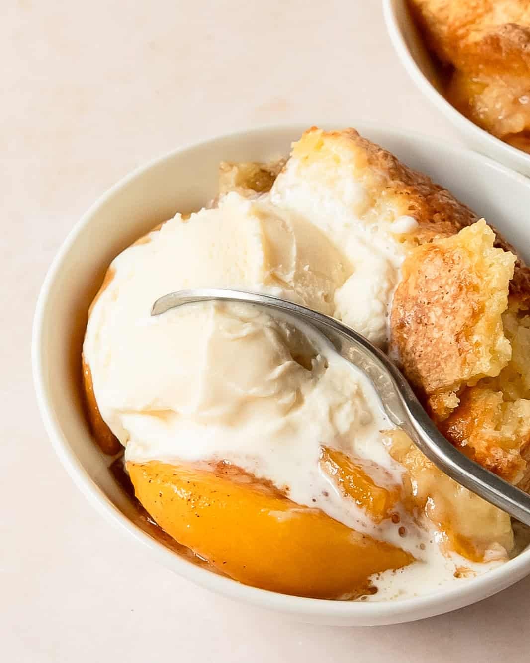 Peach cobbler topped with melting vanilla ice cream.