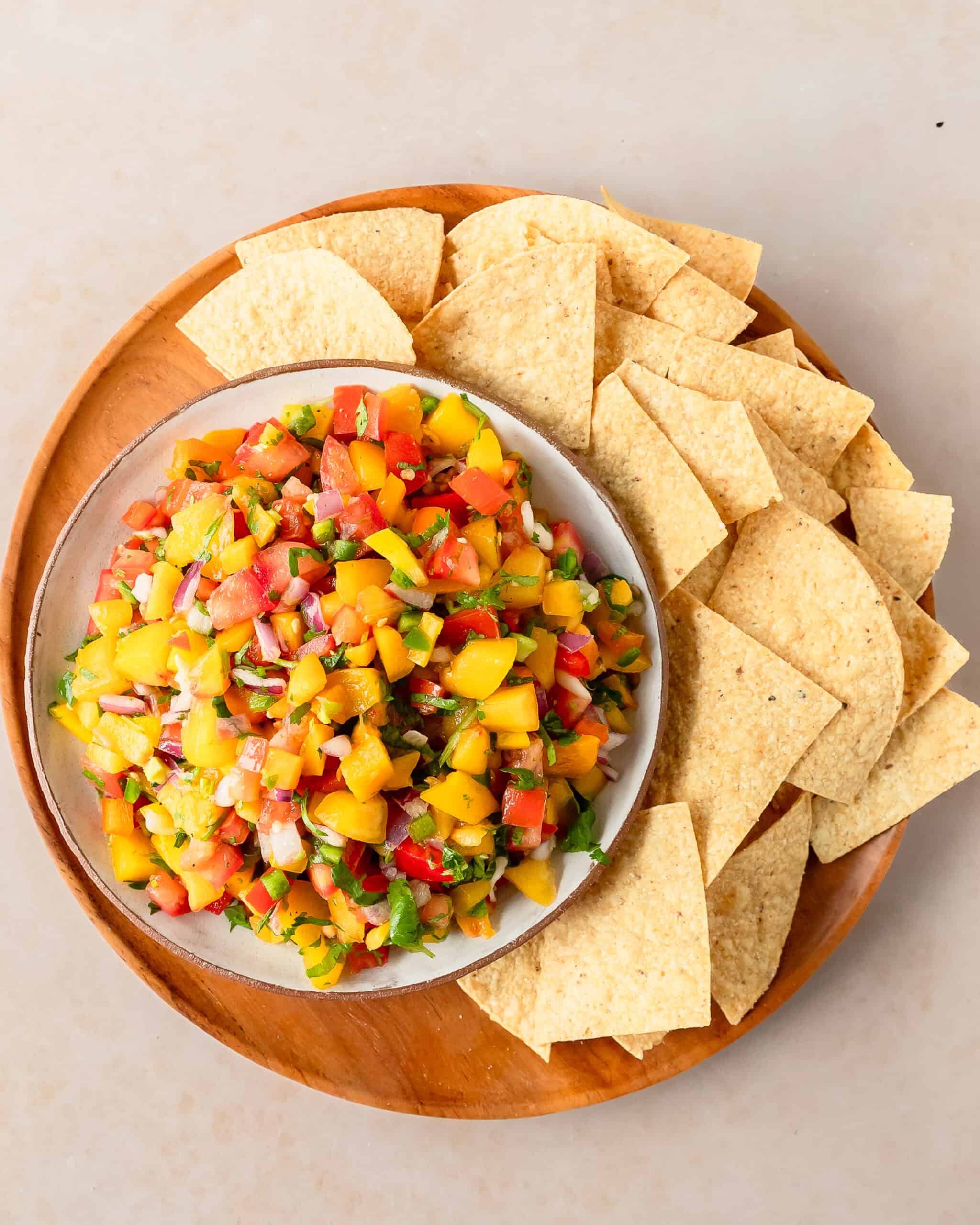 Homemade peach salsa with juicy peaches and colorful vegetables served with tortilla chips.