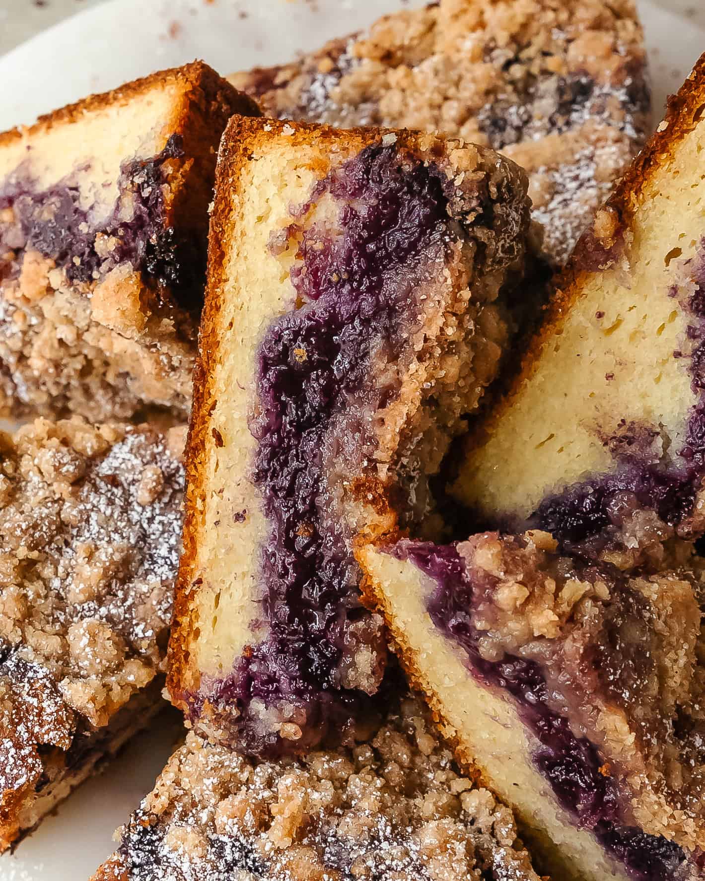 Warm slice of blueberry crumb cake with visible melted blueberries inside.