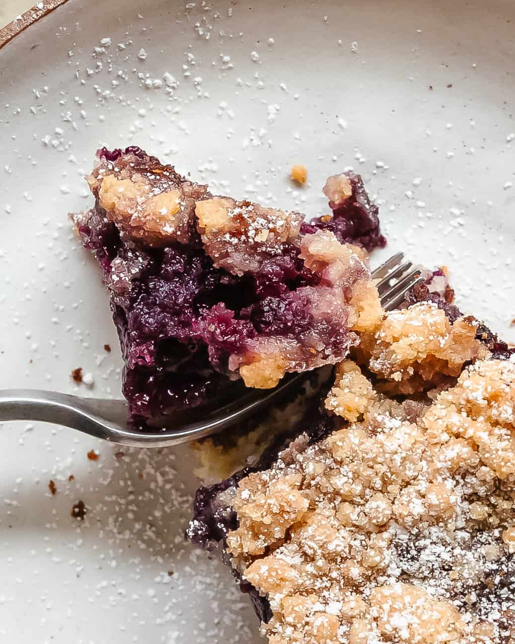 Close-up texture of blueberry crumb cake showing buttery crumb and baked blueberries.