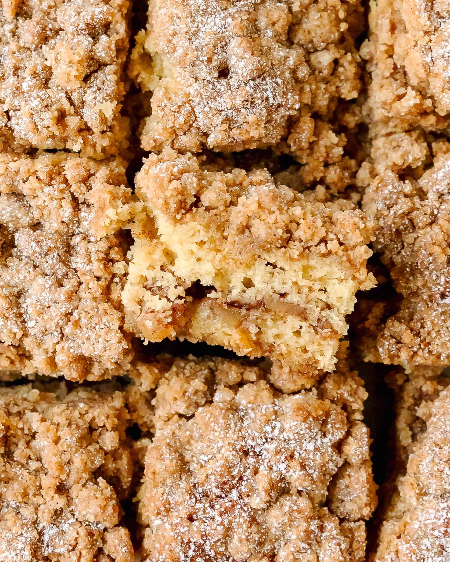 Close up of moist coffee cake with sweet apple pieces and crumble topping.