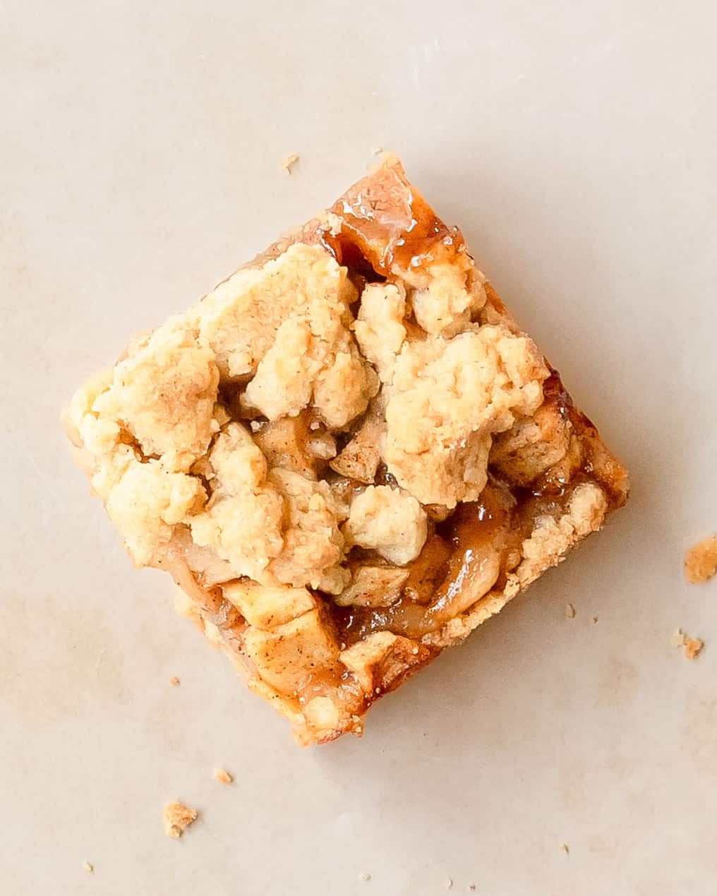 Slice of apple pie bar with tender cinnamon spiced apples and crumb topping.