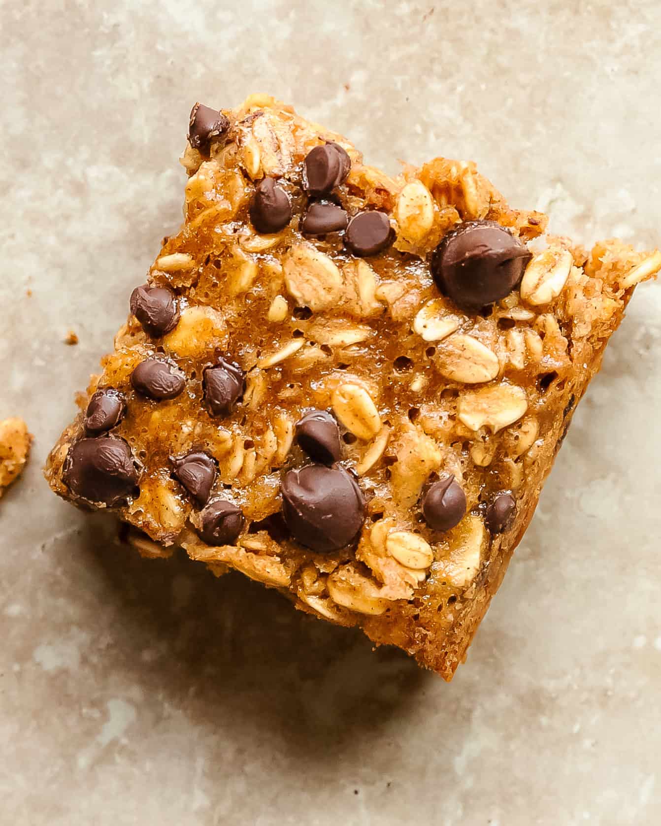 Close-up of a freshly baked oatmeal bar with golden edges and chocolate chips.