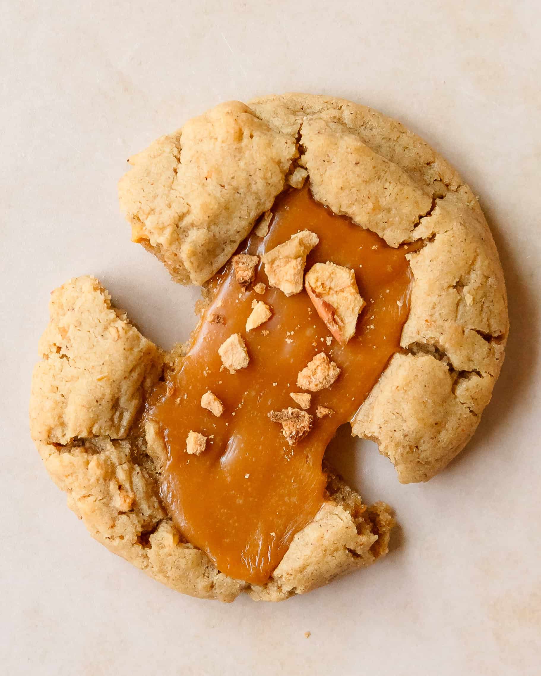 Soft caramel apple cookie pulled apart to show gooey caramel stretched across the cookie.