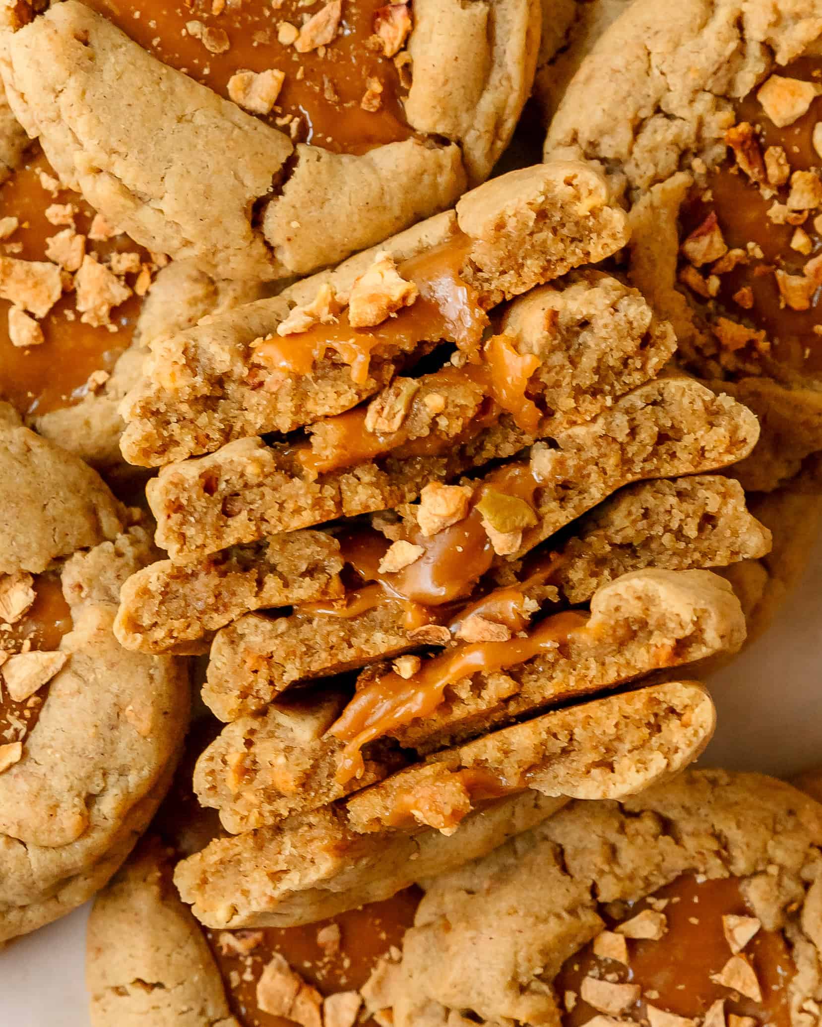 Soft caramel apple cookie broken open to show chewy caramel and dried apples.
