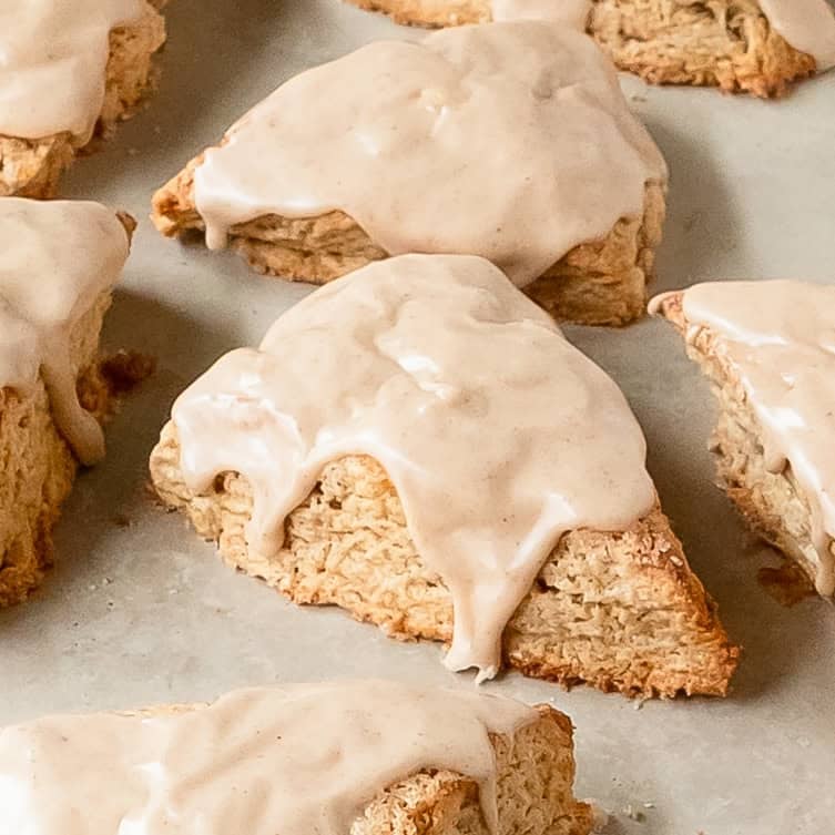 A bakery-style display of freshly baked cinnamon scones with icing.