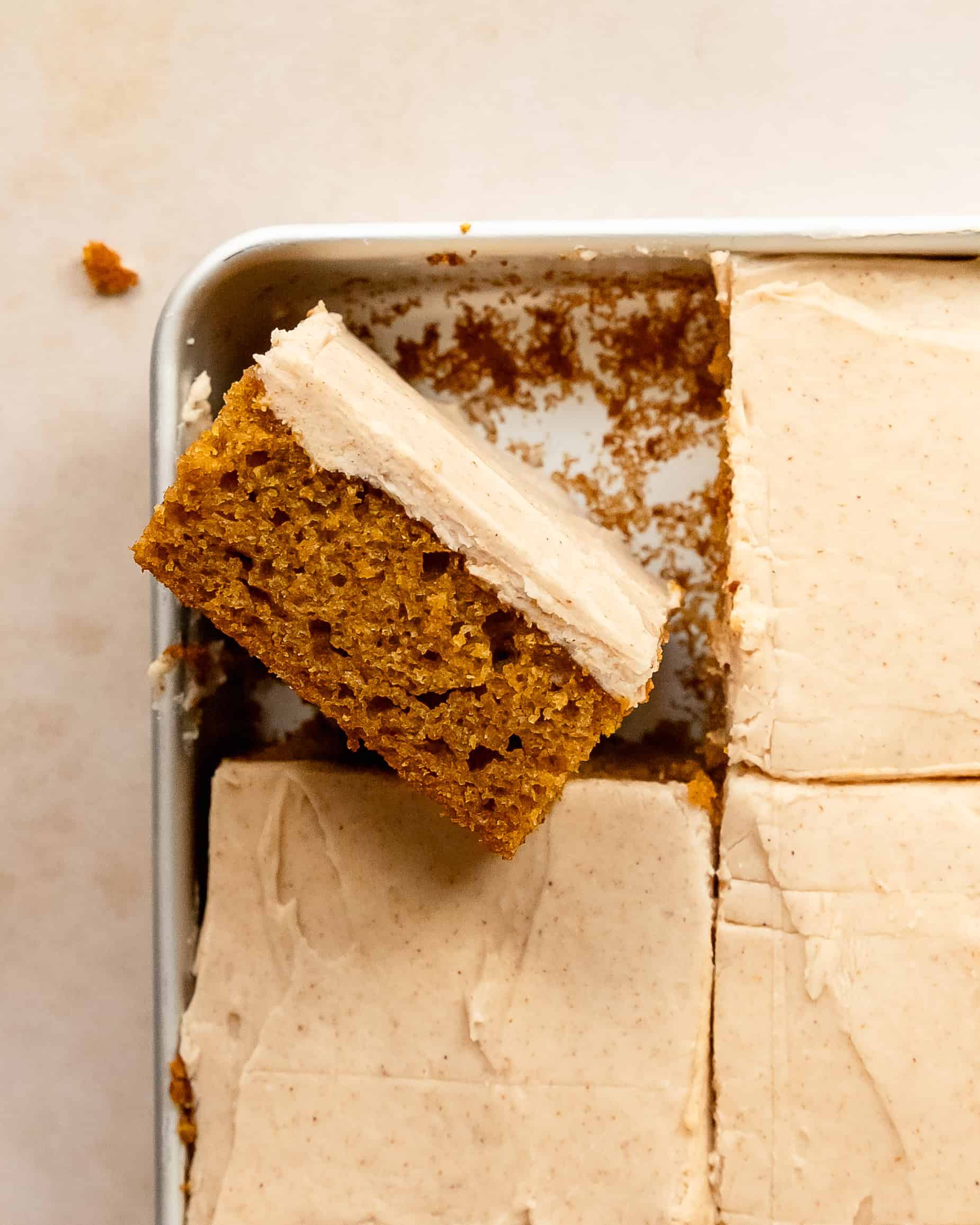 A slice of pumpkin cream cheese bars facing up showing the pumpkin cake and the frosting.