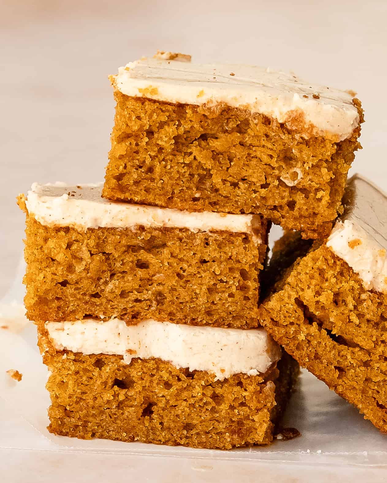 Stack of fluffy and moist frosted pumpkin bars.