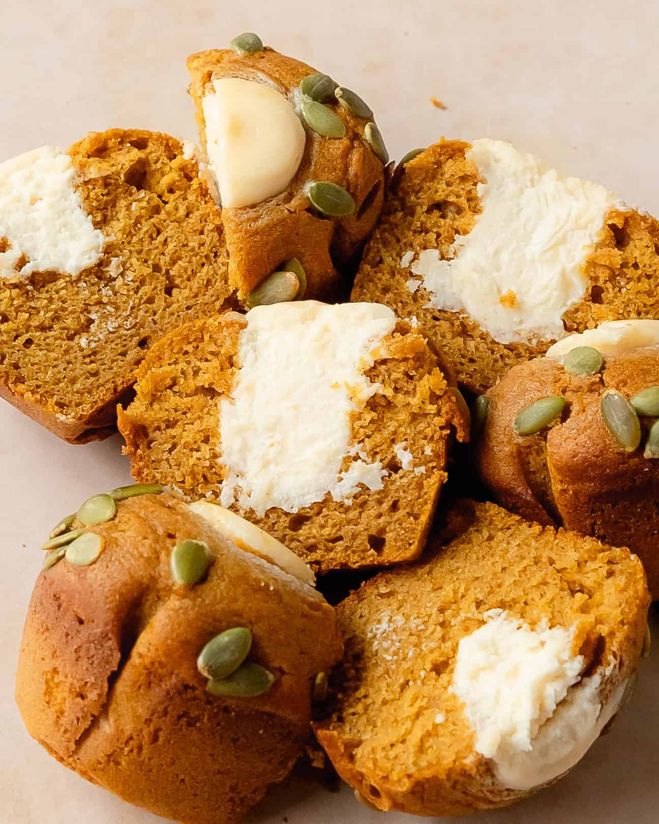 Broken pumpkin cream cheese muffin showing its soft pumpkin crumb and creamy center.