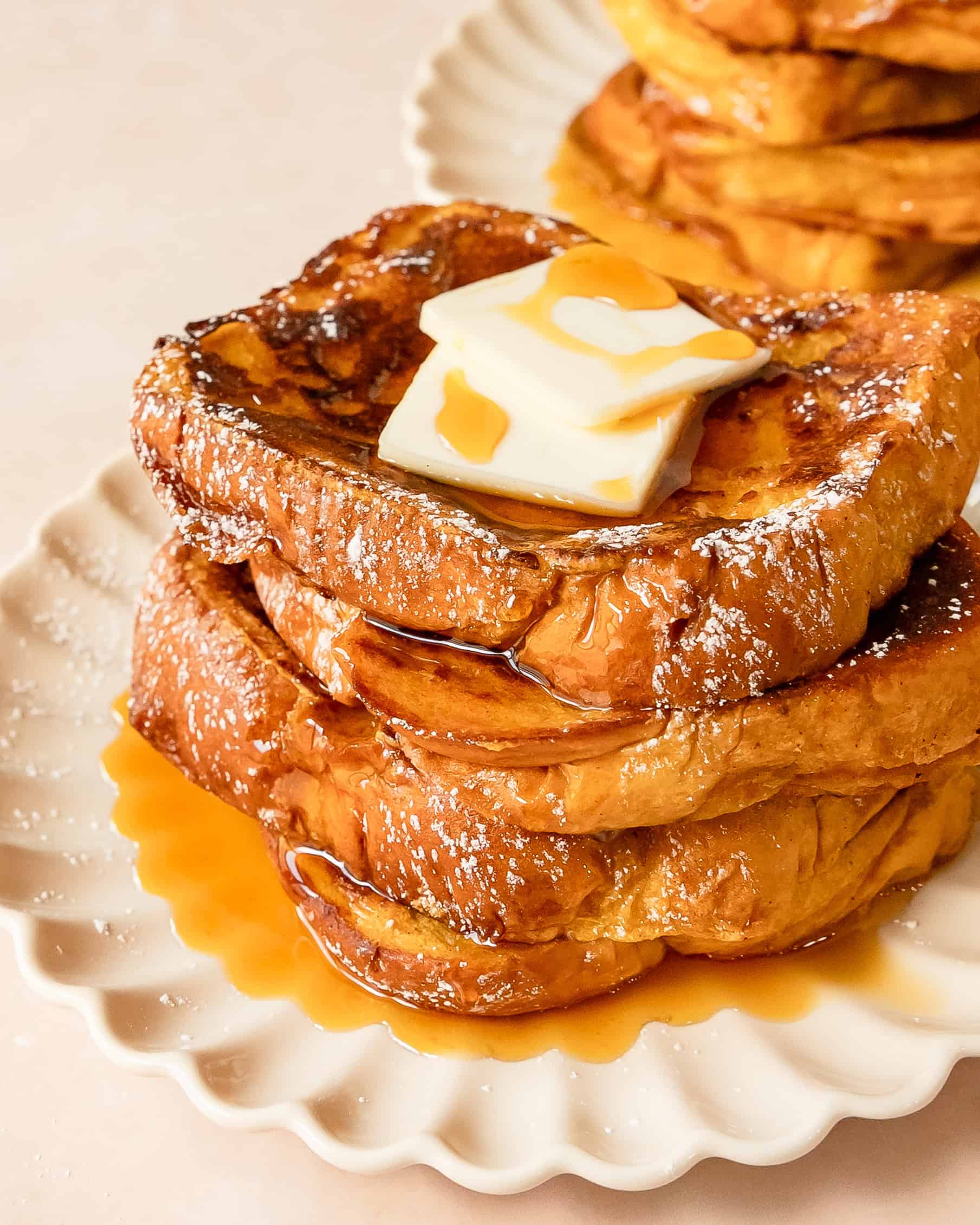 Golden pumpkin French toast topped with powdered sugar and maple syrup and pumpkin butter.