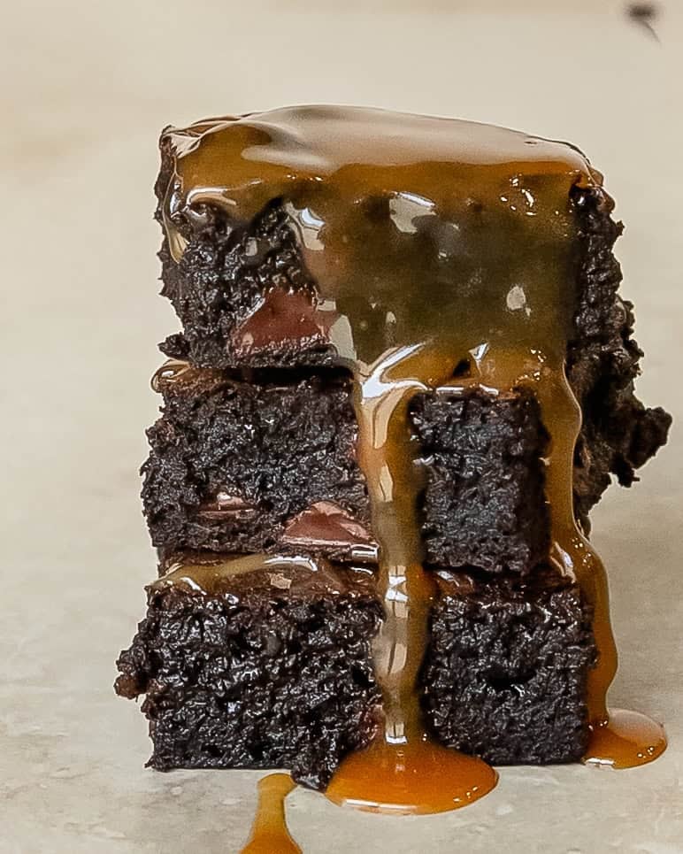 Stack of fudgy brownies with salted caramel dripping down the sides.