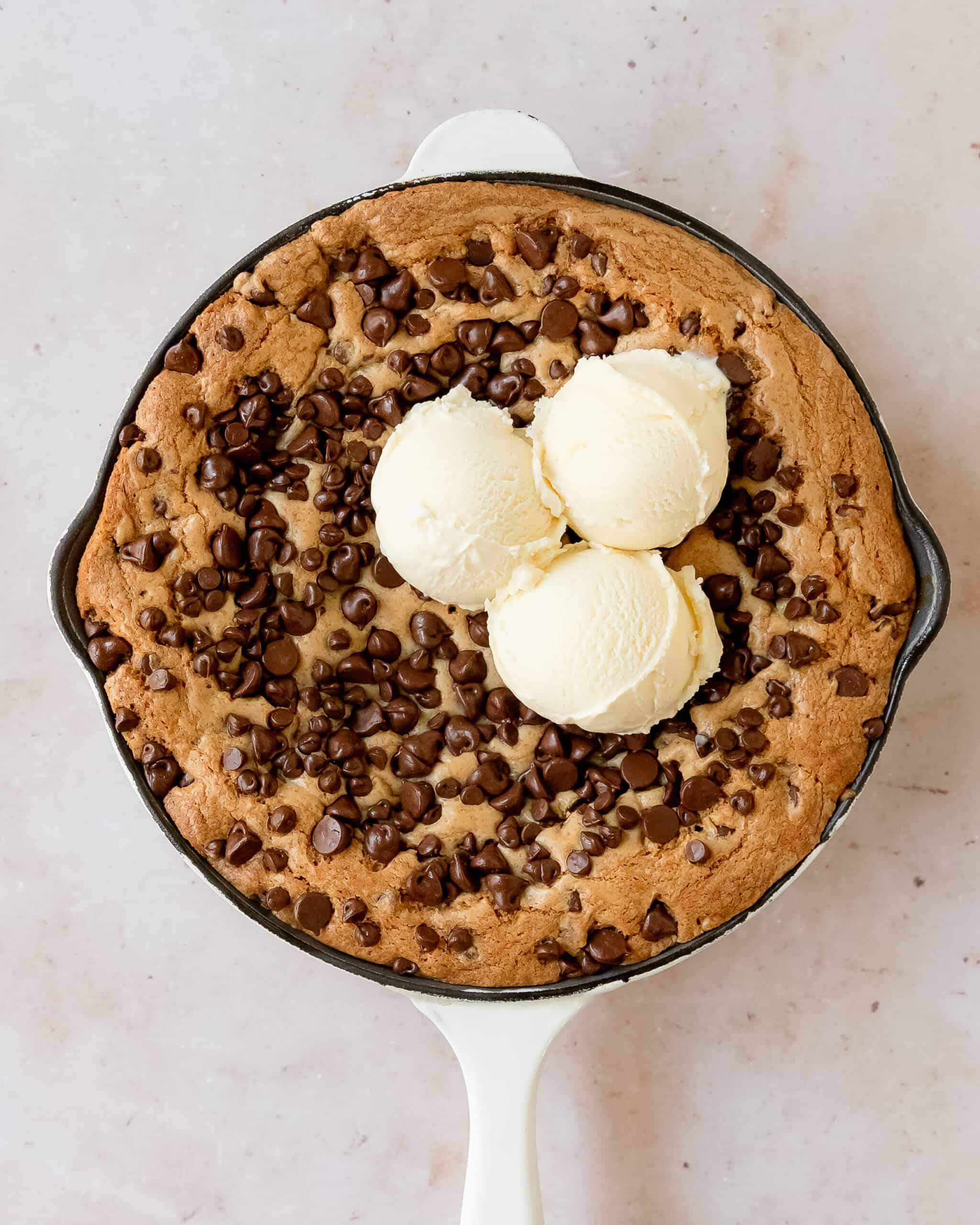Warm chocolate chip skillet cookie topped with scoops of vanilla ice cream.