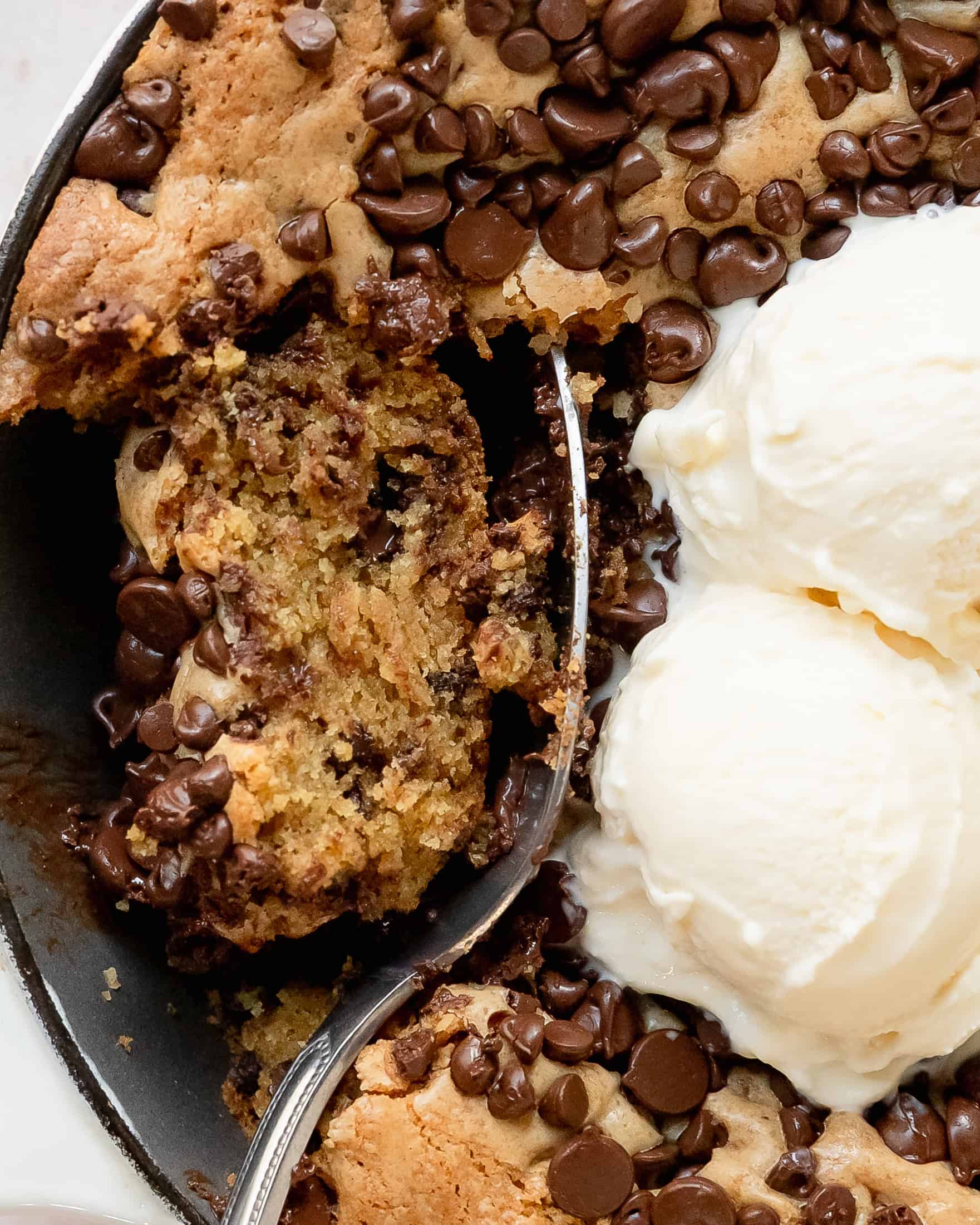 Close-up of a gooey chocolate chip skillet cookie with a soft center.